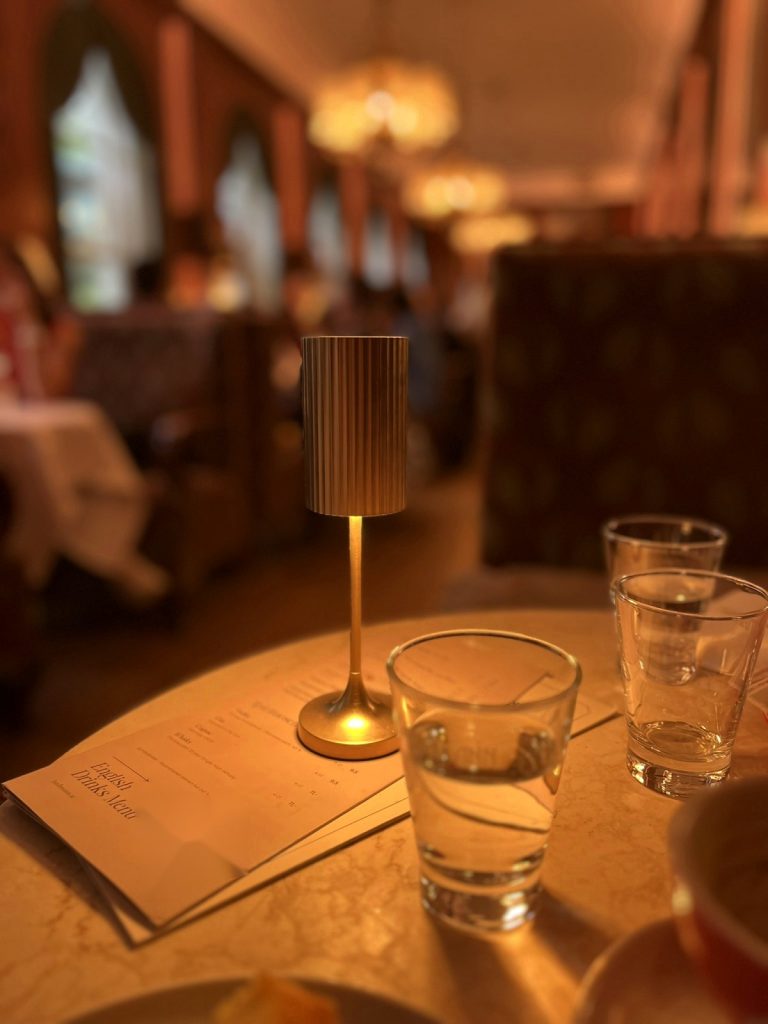 Stillleben in einem Wiener Kaffeehaus: Tischlampe, Wassergläser und Getränkekarte auf Marmortisch