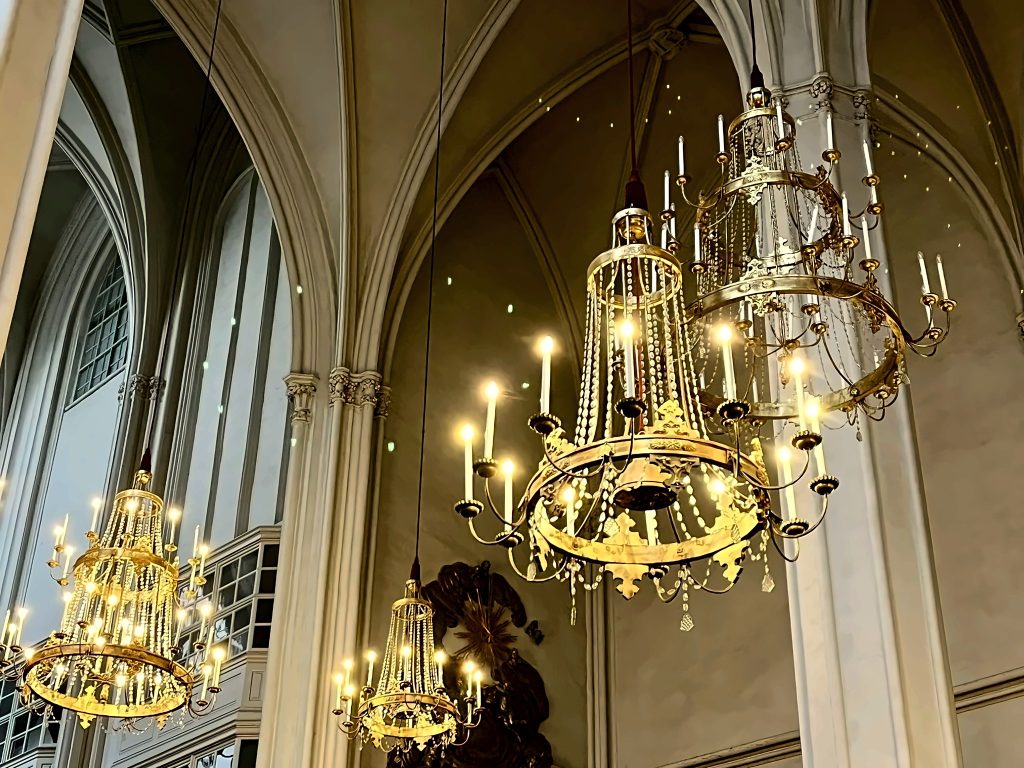„Goldene Kronleuchter im gotischen Gewölbe der Augustinerkirche Wien